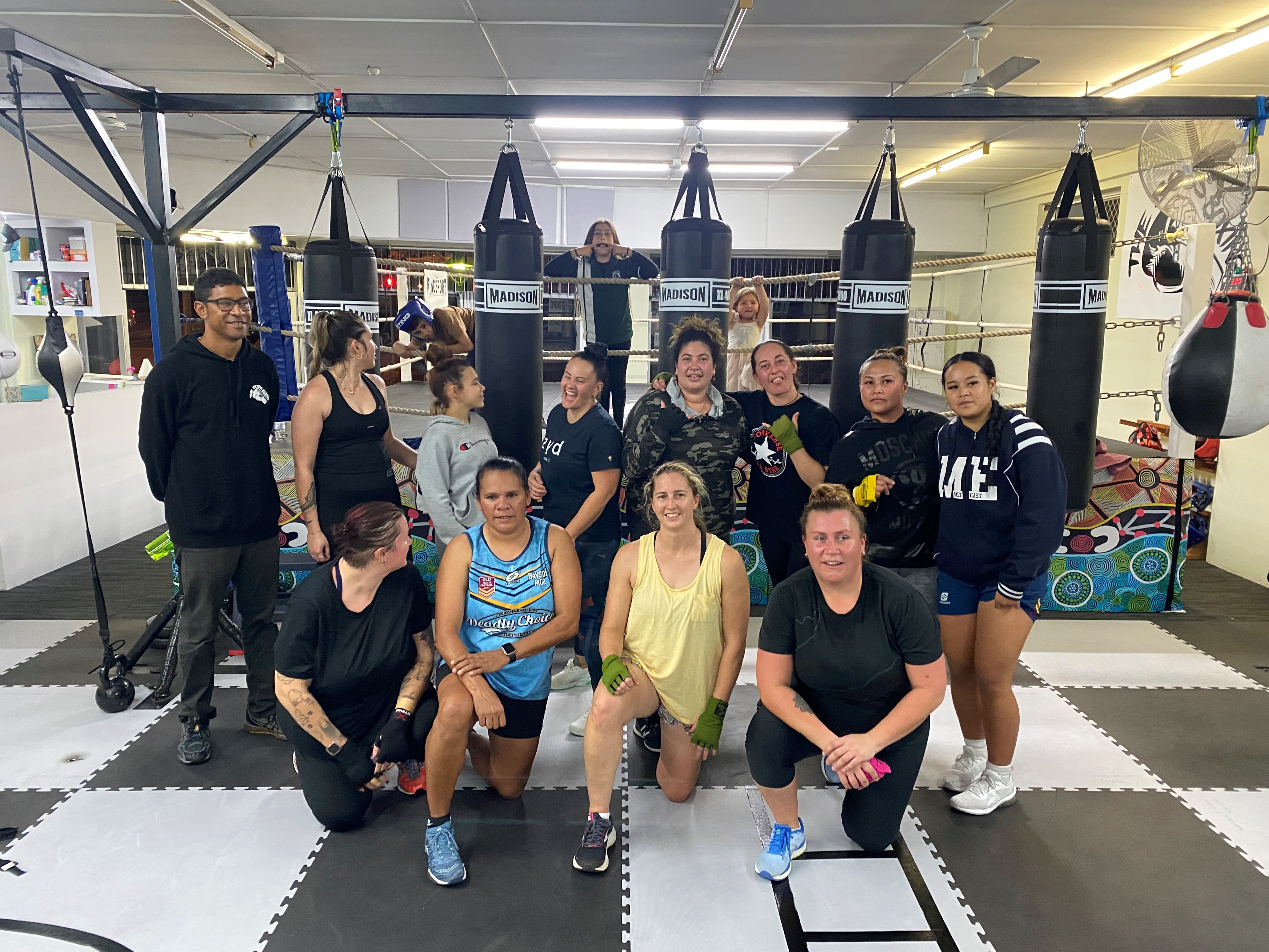 Group of boxers posing in front of punching bags