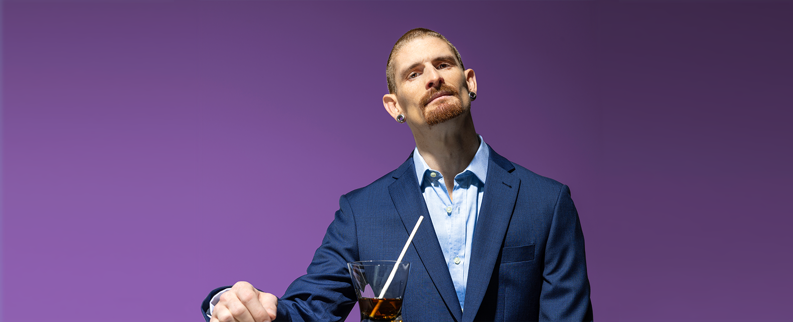 A man in a suit with a drink in front of him