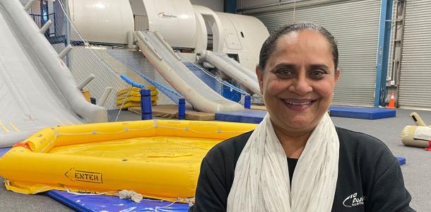 Harsha Patel standing in front of aviation training equipment - rafts and evacuation slides.  